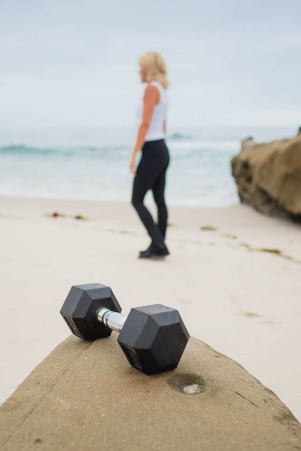 A dumbbell resting on a sandstone rock with the ocean behind