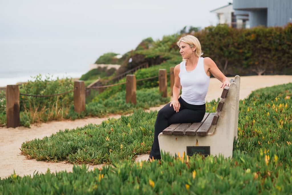 Rose Martin seated on a bench along a coastal walking path